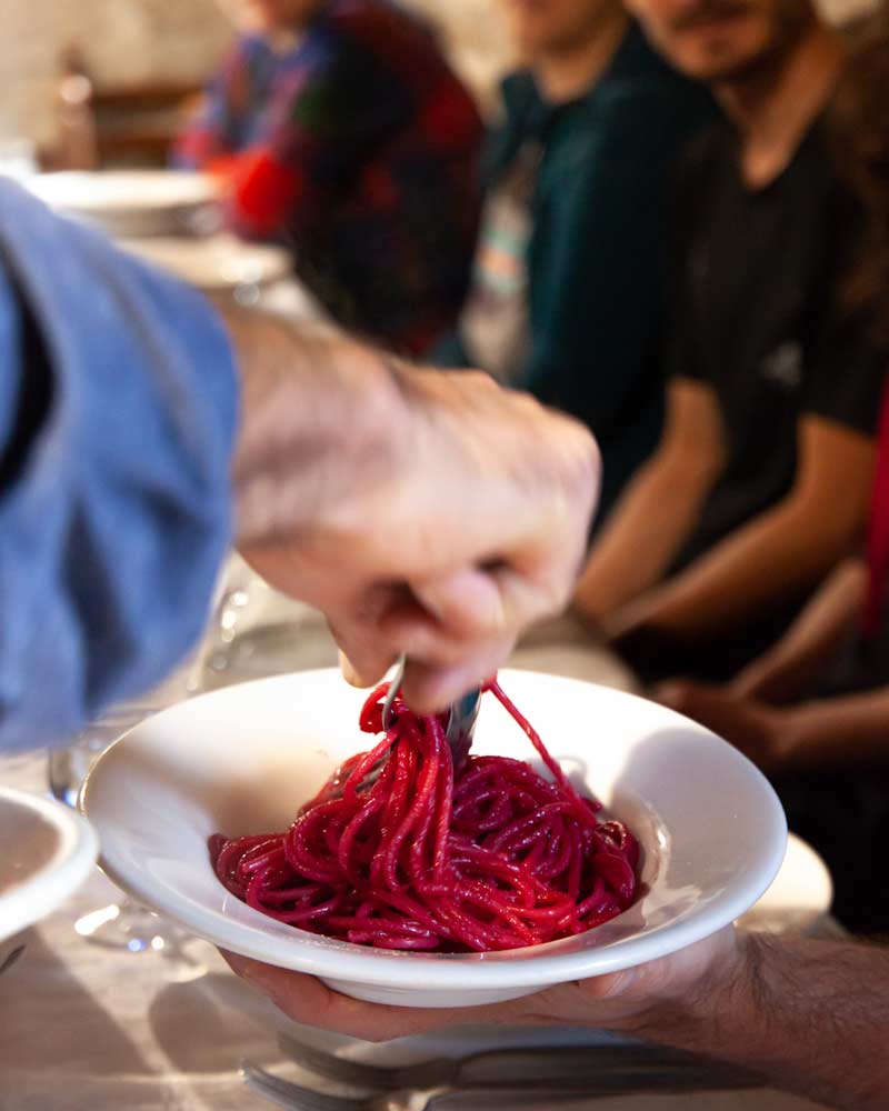 服务员端出一盘紫色的意大利面，这盘意大利面是用甜菜根煮的