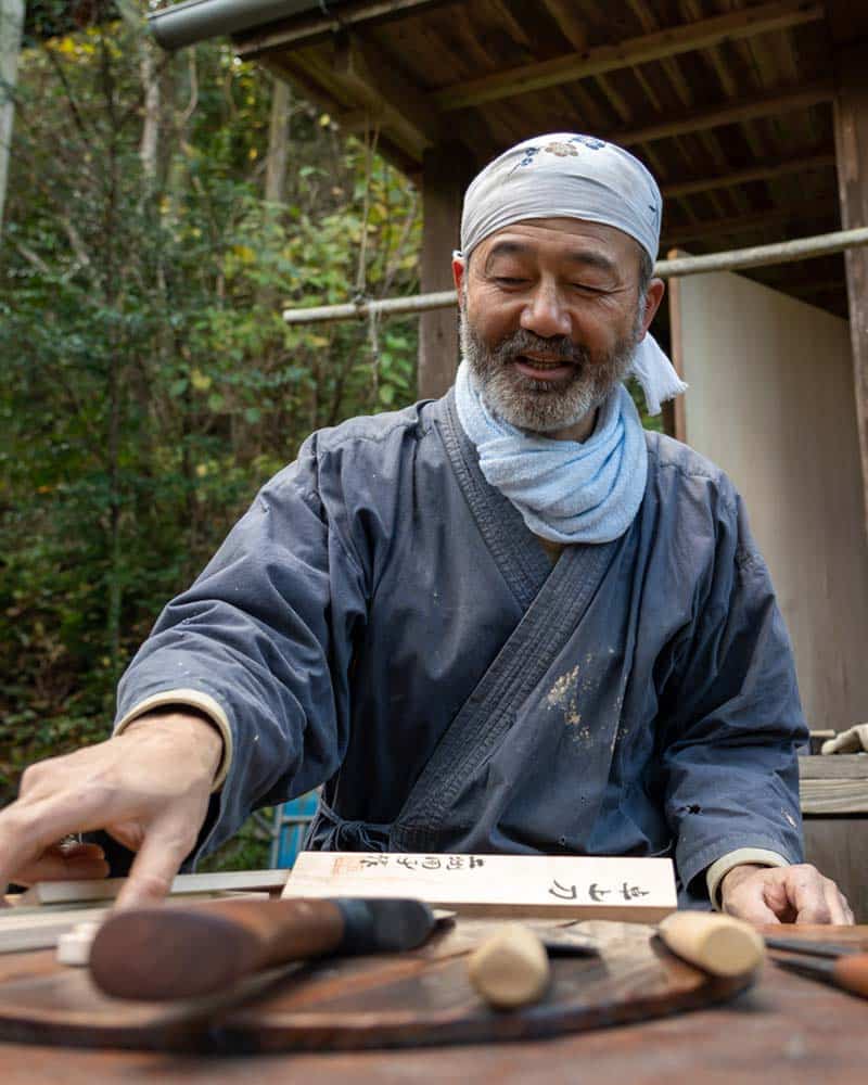 在日本高知县的传统制刀工艺中，铁匠拿着刀坐在桌子旁