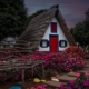 桑塔纳传统的茅草屋，一个尖尖的三角形房子，有彩色的蓝色和红色的窗户，外面有鲜花