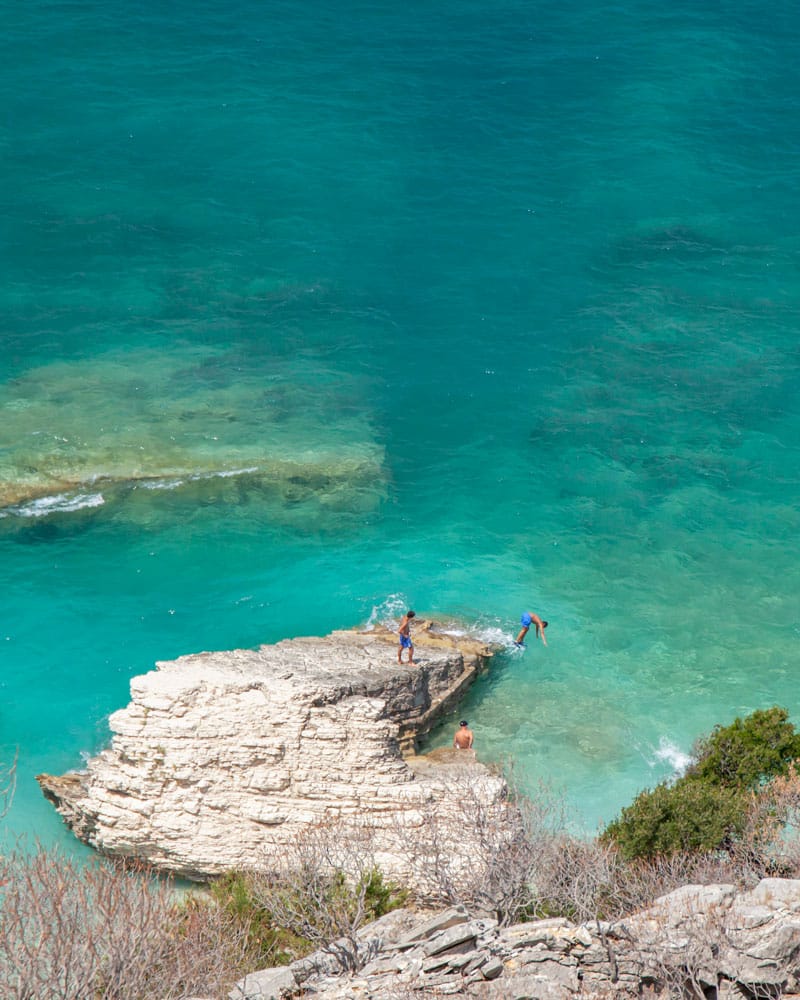 人们从岩石上跳入水中，从四月开始，阿尔巴尼亚的海滩变得更加诱人