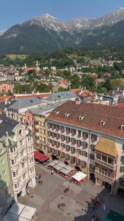 From a tower, looking down on the main square and colourful buildings with mountain peaks – some with a little of snow even though its summer – are behind