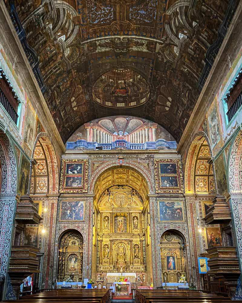 教堂里有华丽的金色和蓝色的绘画和瓷砖，还有一个略微弯曲的天花板，上面有复杂的木制品
