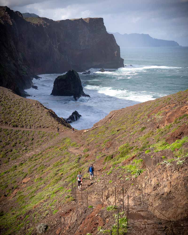 一对夫妇沿着小径爬到庞塔São Lourenço，巨大的波浪冲击着下面的悬崖
